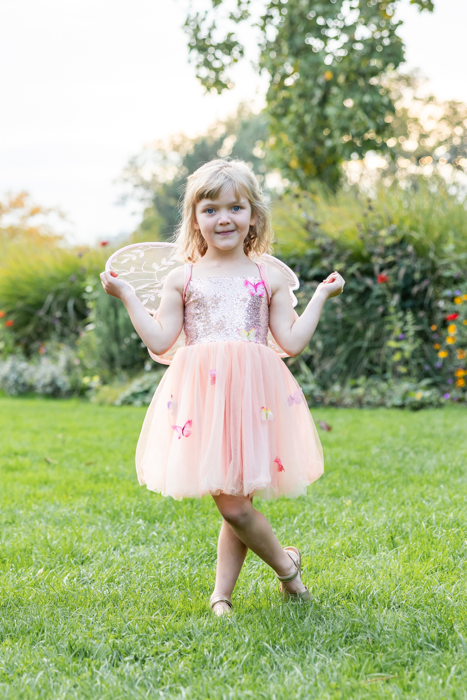 Young girl in a fairy costume with wings standing on grass