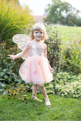 Young girl in a fairy costume with wings standing in a garden.